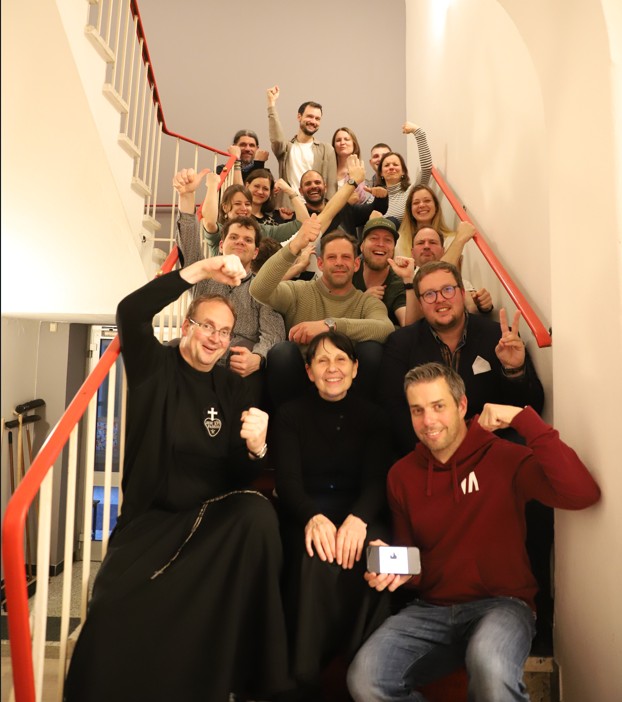 Eine Gruppe junger Menschen sitzt auf einer Treppe und hebt die Hände